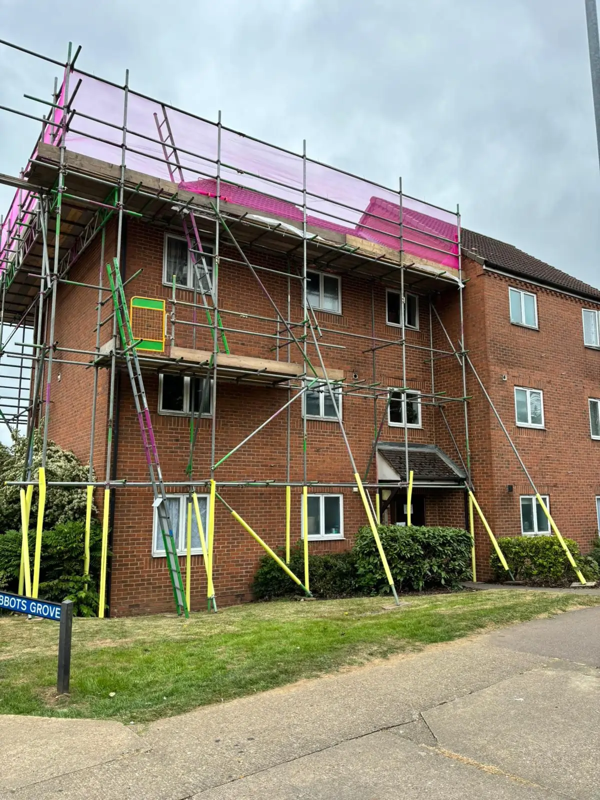 Professional scaffolders Dartford & Kent installing scaffolding around a three-storey brick residential building for roof and exterior works.